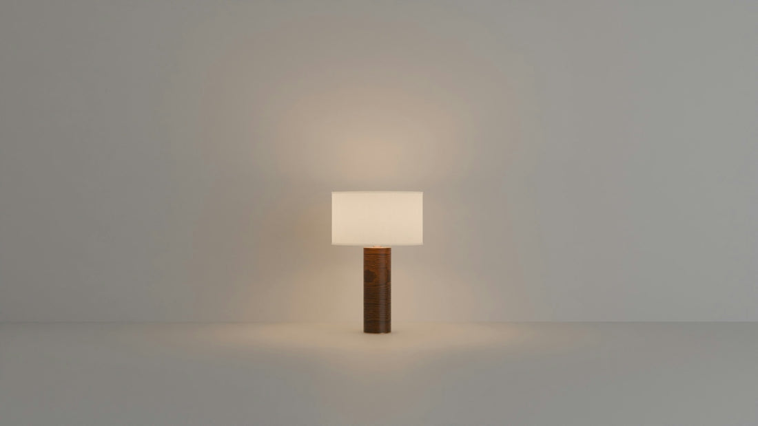 A modern lamp with a wooden base glows softly