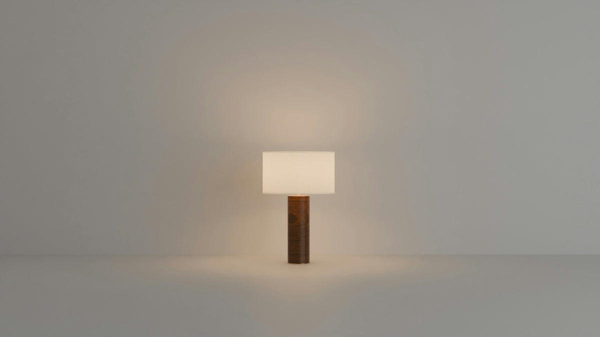 A modern lamp with a wooden base glows softly