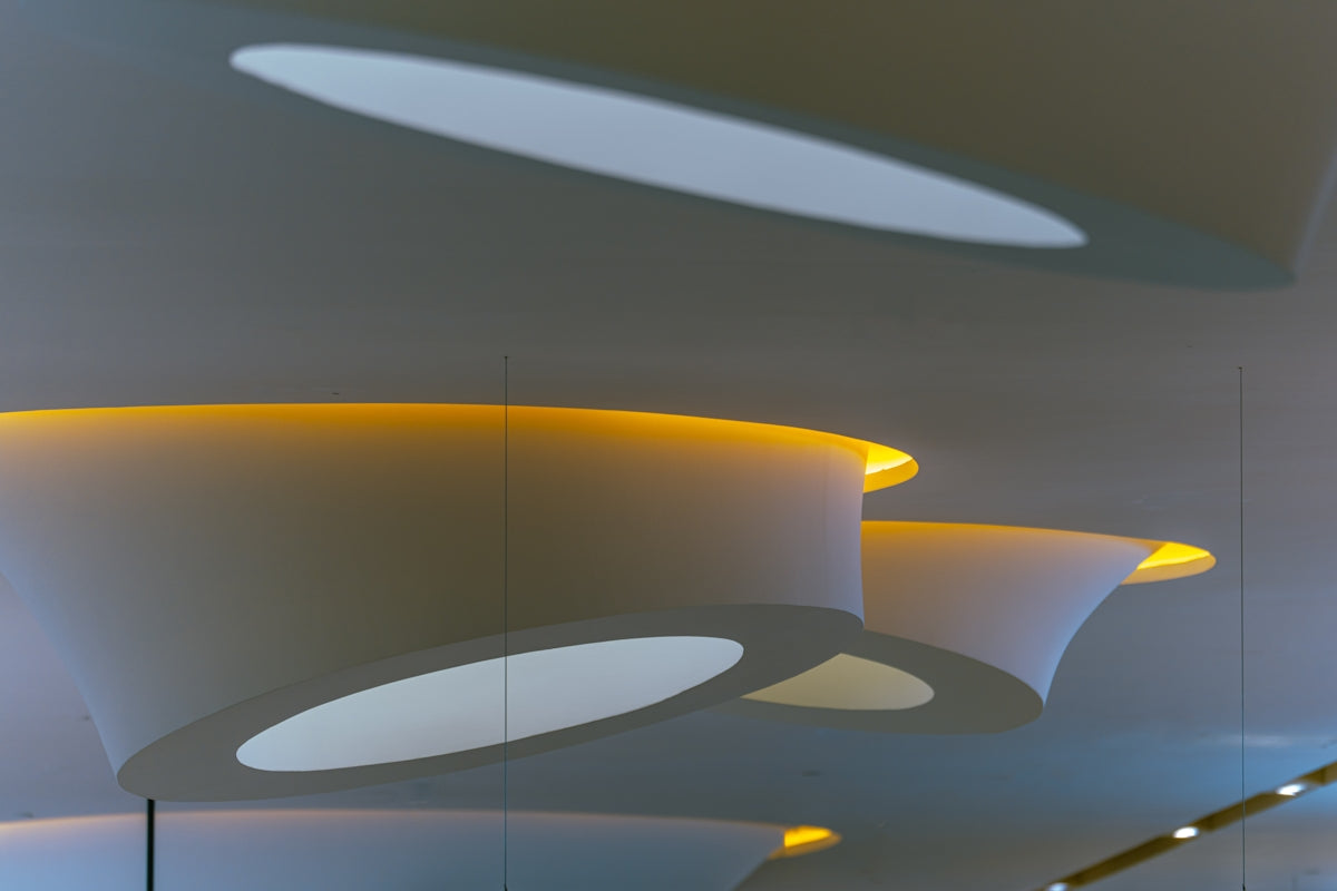Abstract white ceiling structures with warm yellow recessed lighting